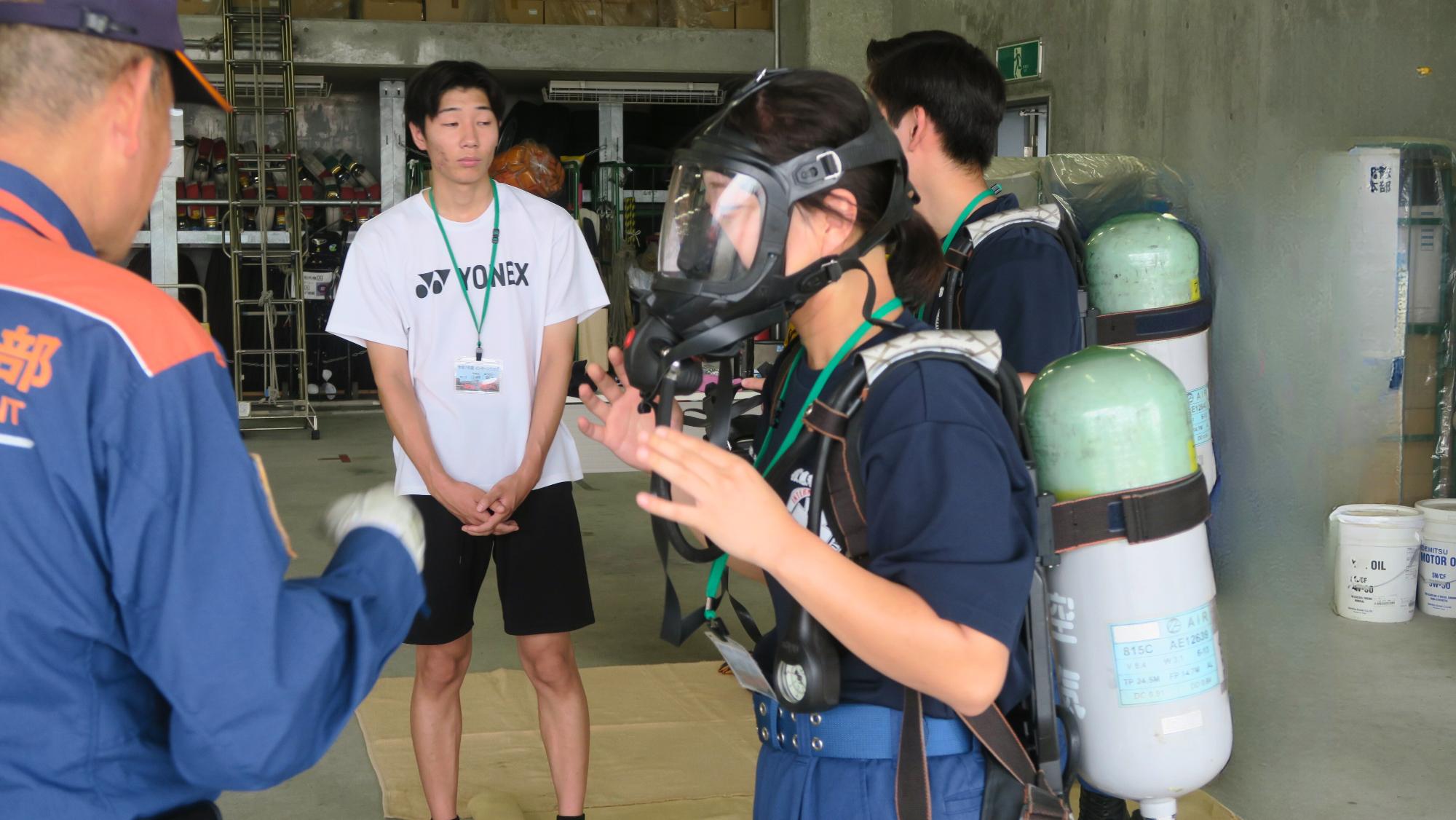 消防士の指導のもと参加者が空気呼吸器を背負い、面体を装着している写真