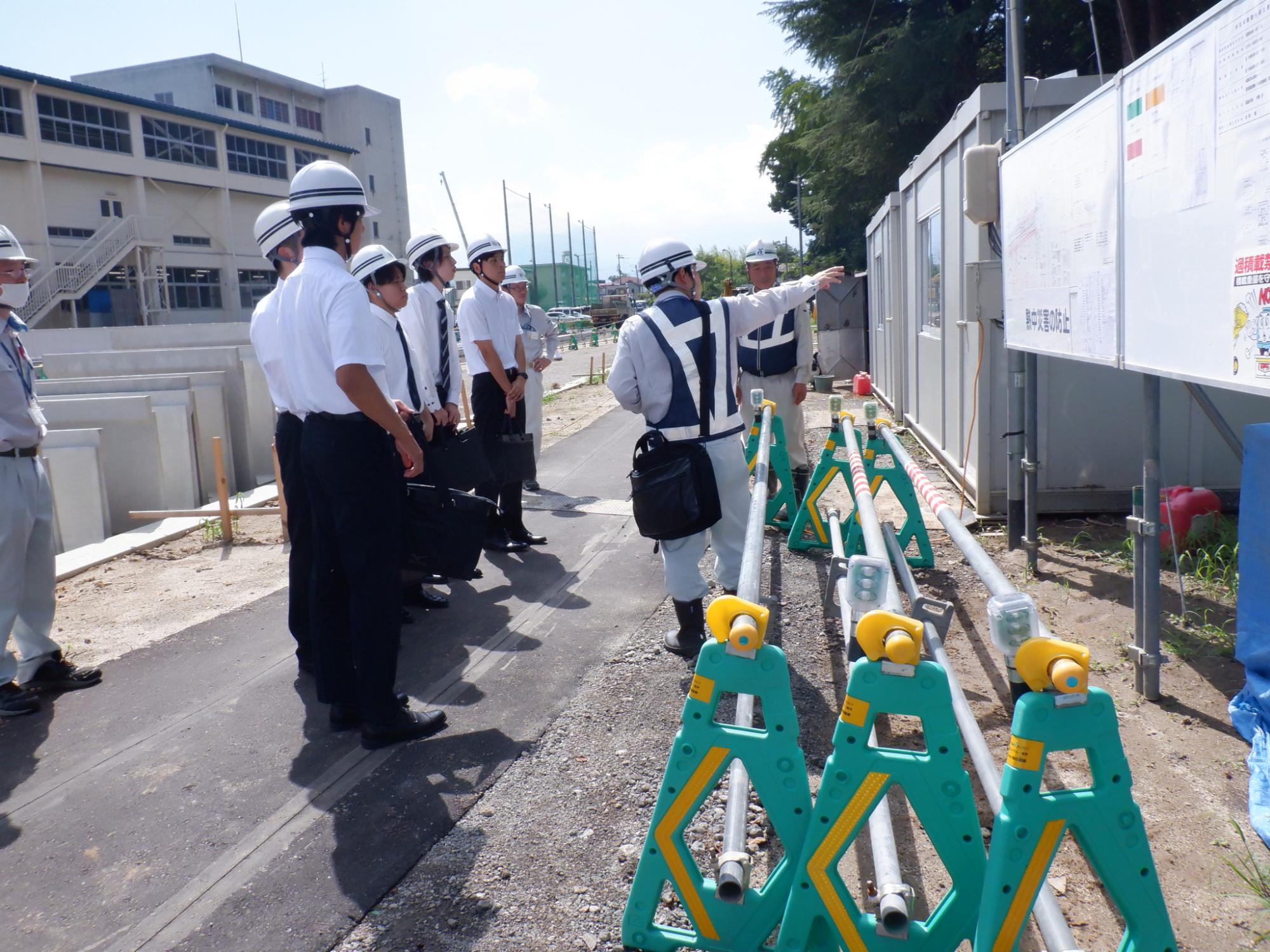ヘルメットをかぶった参加者が現場見学をする様子の写真