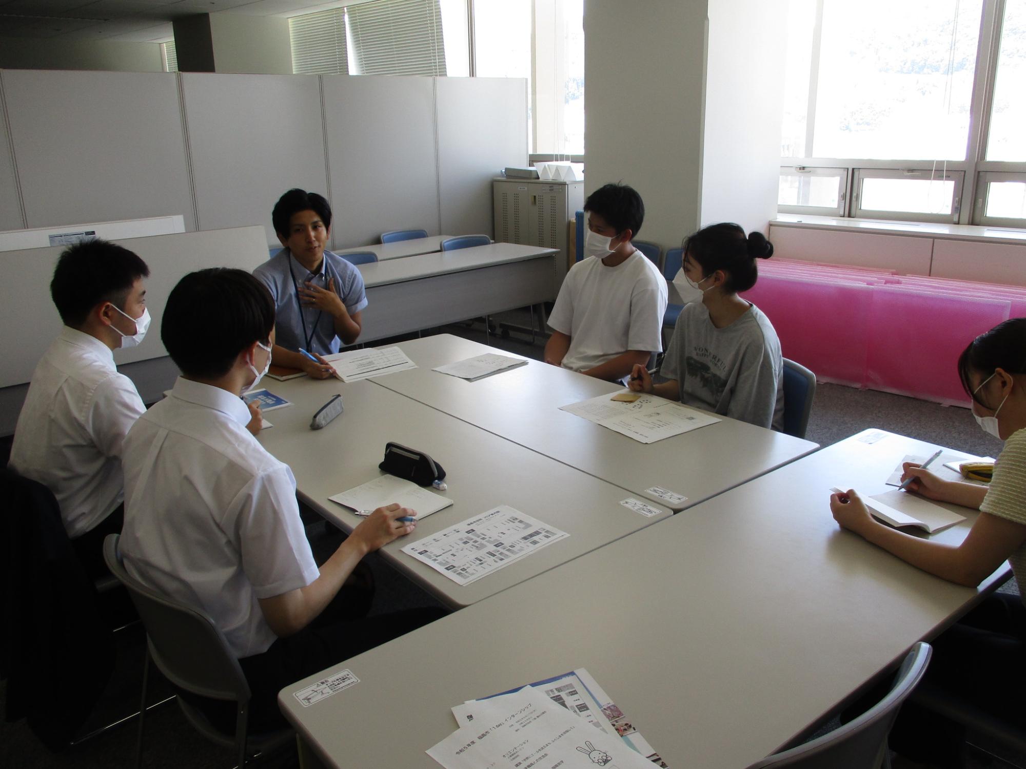 テーブルを囲んで男性職員が前に座り若手職員との交流会が行われている写真