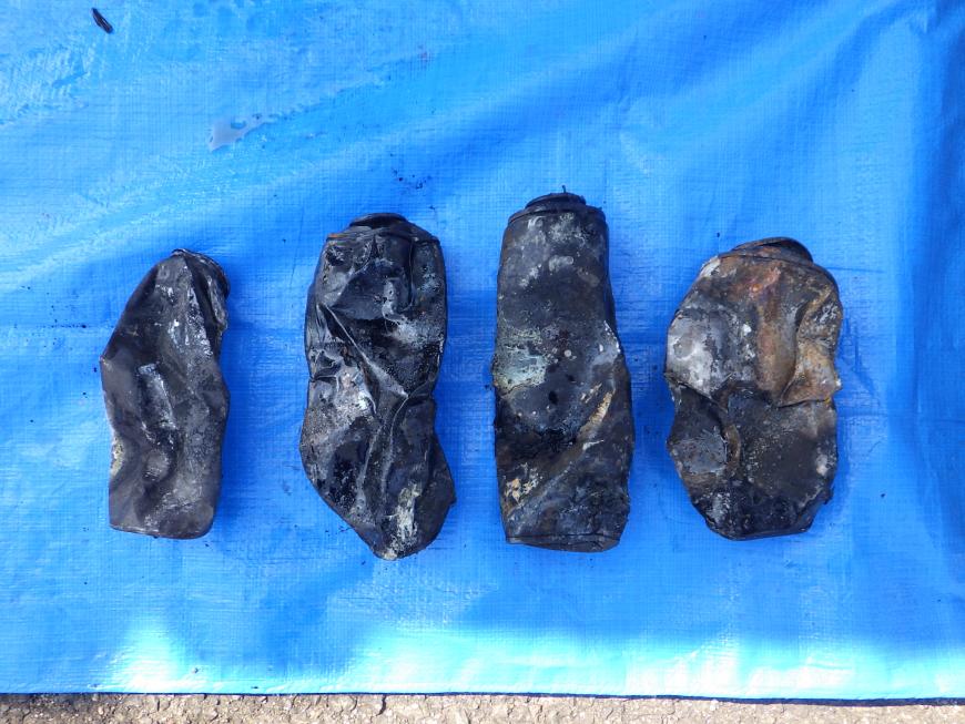 ブルーシートの上に焼けて黒くなったカセットボンベが4つ置かれた写真