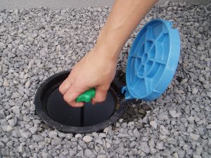 水抜栓の蓋が開けられ、中にあるハンドルを手で握りまわしている様子を写した写真