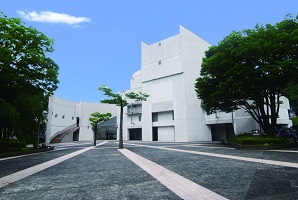 両側に木々が植えられた奥にある白い外壁をしたふくしん夢の音楽堂の外観写真