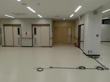 左奥に2つの白い引き戸があり、中央奥に茶色の扉が設置された何も物が置かれていない室内の写真