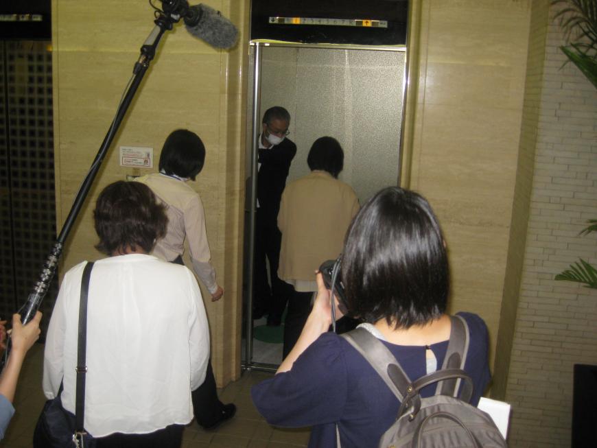 係の男性がエレベーターの扉を開け、参加者の方々がエレベーターの中に入ろうとしている様子の写真
