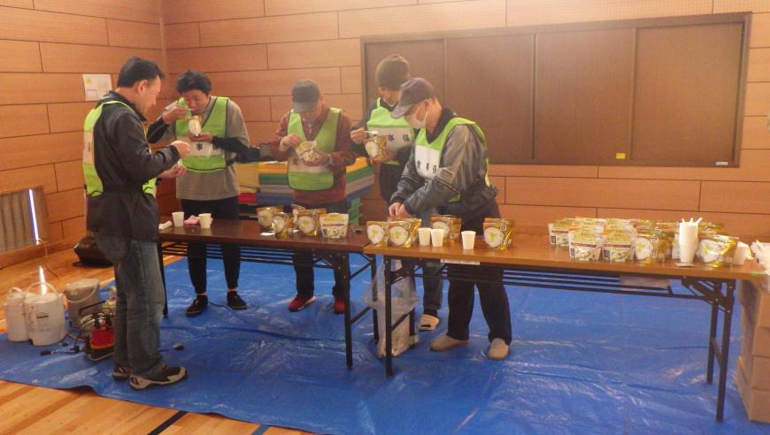 「食事係」の緑のビブスをつけた関係者の方々が、非常食の試食をしている様子を写した写真