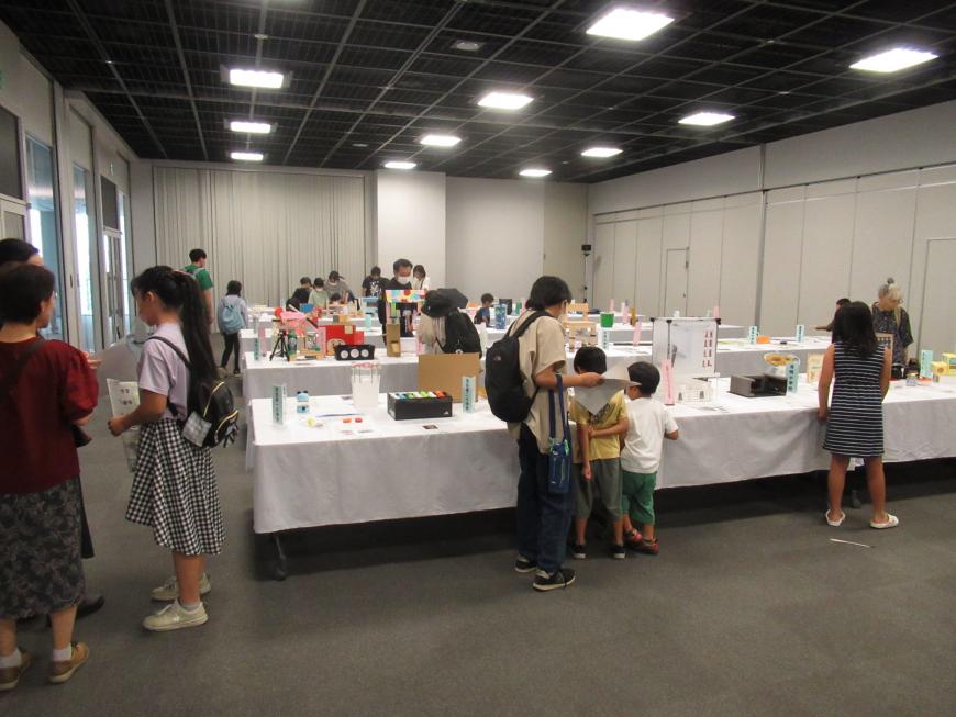 室内の会場に展示された沢山の作品を子供たちや親子連れが見ている様子の写真