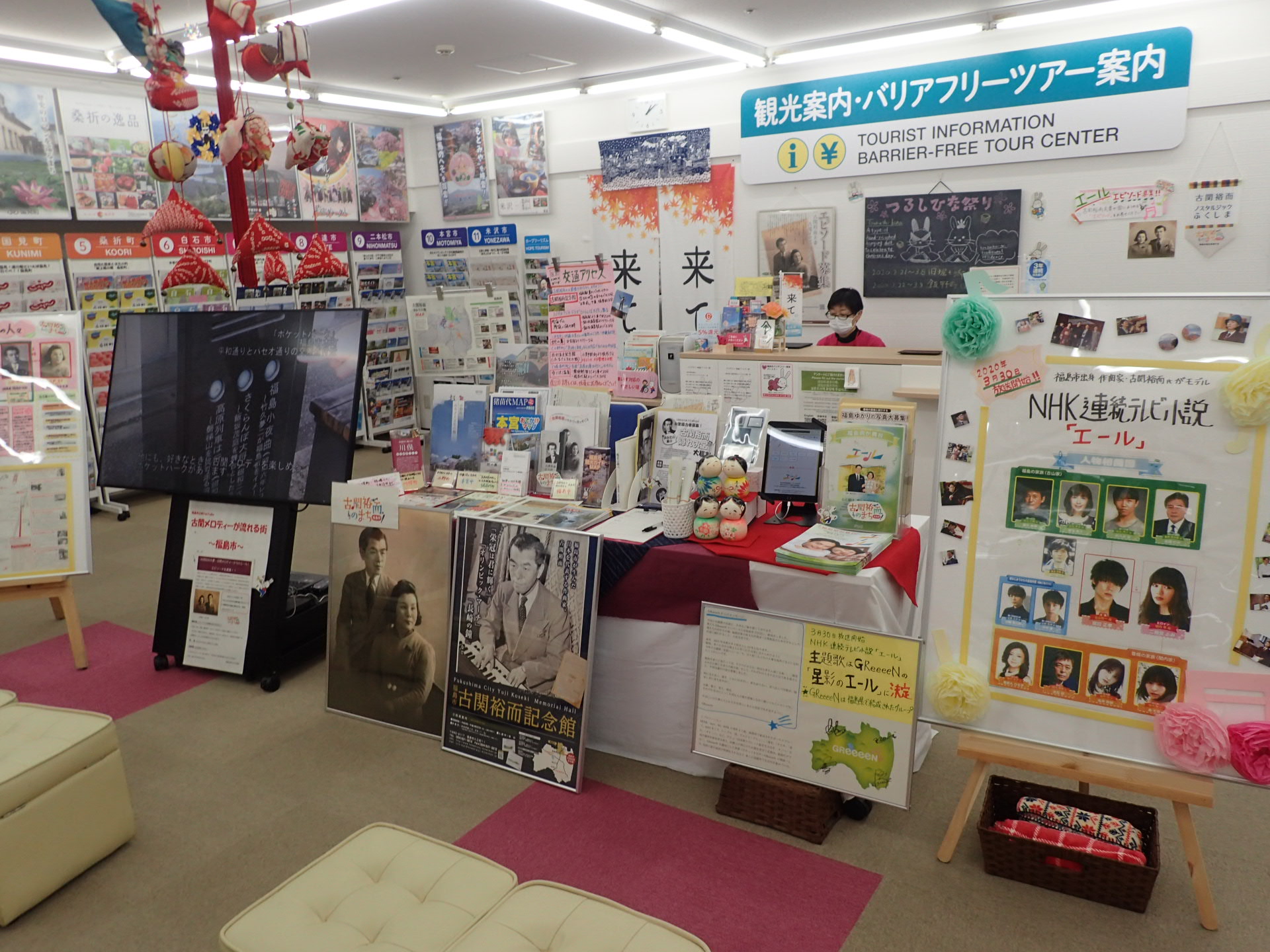 受付カウンターの前に沢山のポスターが貼られ、パンフレットが並んでいる観光案内所の写真