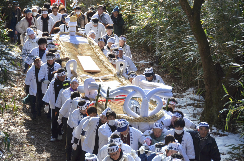 大きなわらじをたくさんの人達で持ち上げ運んでいる写真