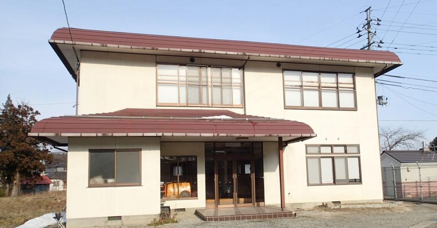 赤茶色の屋根で白壁の2階建ての水原生活改善センターの建物外観の写真