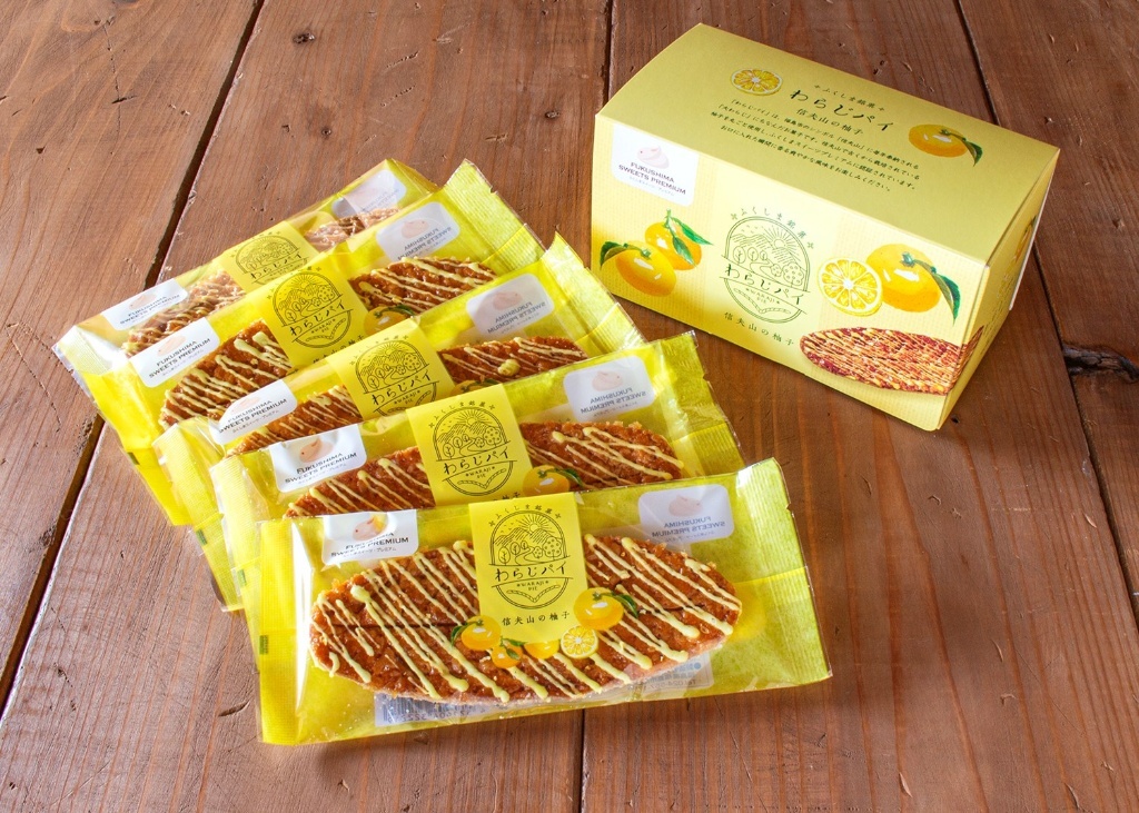 黄色いパッケージに個包装されたわらじ型のパイ5つと、わらじパイの黄色い箱が並んでいる写真