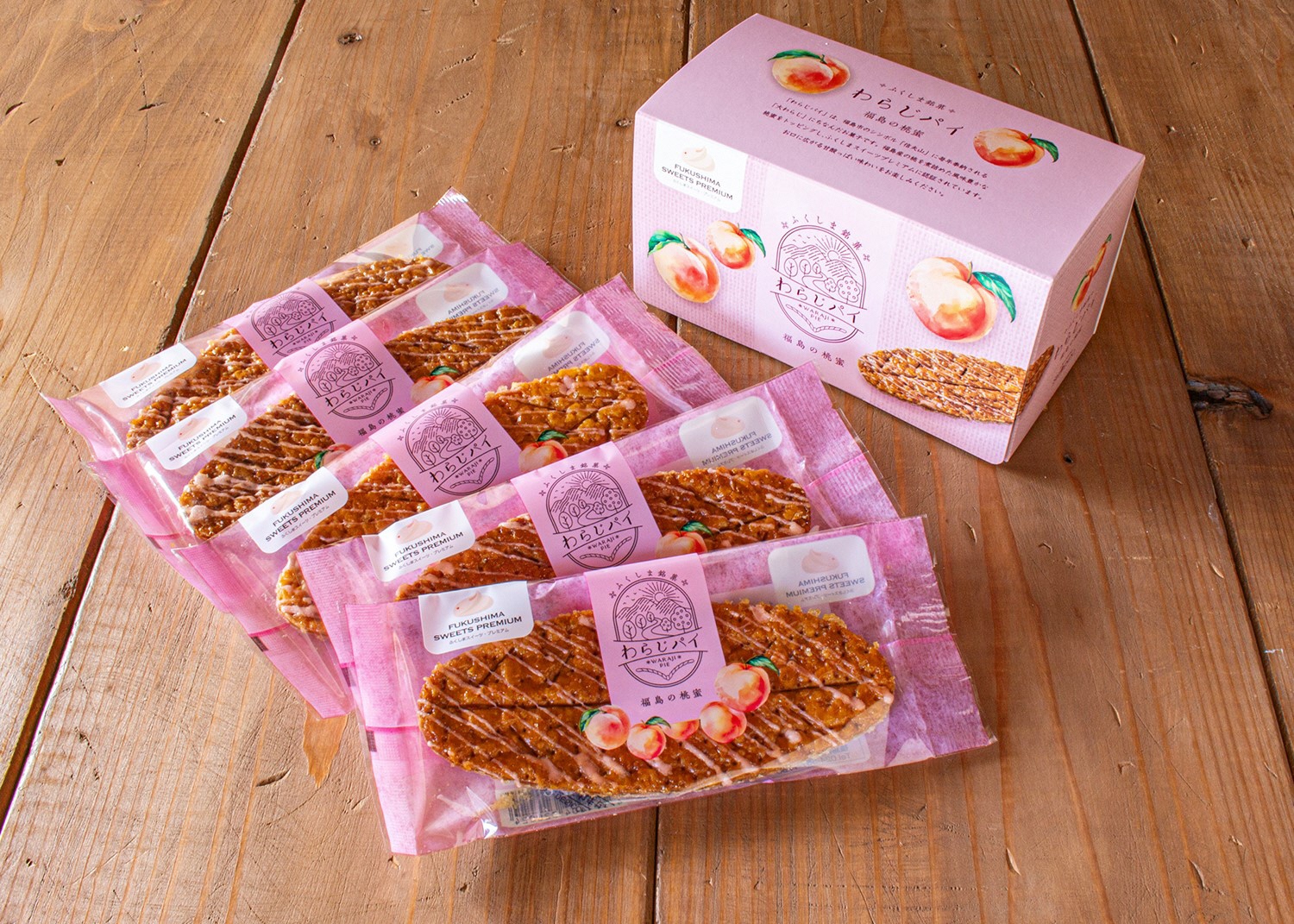 ピンクの色パッケージに個包装されたわらじ型のパイ5つと、わらじパイのピンク色の箱が並んでいる写真