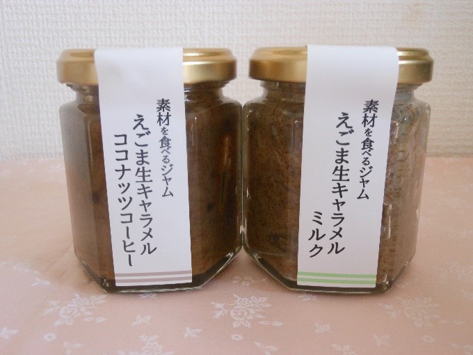 六角瓶の蓋から瓶底にかけて「素材を食べるジャム えごま生キャラメル」と書かれたラベルが貼られた、ミルク味とココナッツコーヒー味の2種類の商品が並んでいる写真