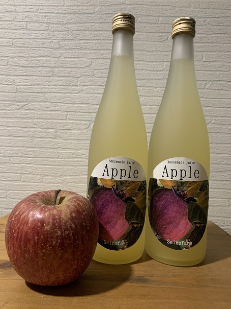 真っ赤なりんごとAppleと書かれたラベルが貼られた2本のりんごジュースの瓶が並んでいる写真