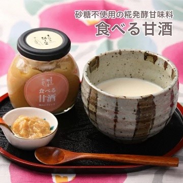 お盆の上に湯飲みに入った甘酒と、「食べる甘酒」と書かれた薄いピンク色のラベルが貼られた瓶と小皿に盛り付けられた商品の写真