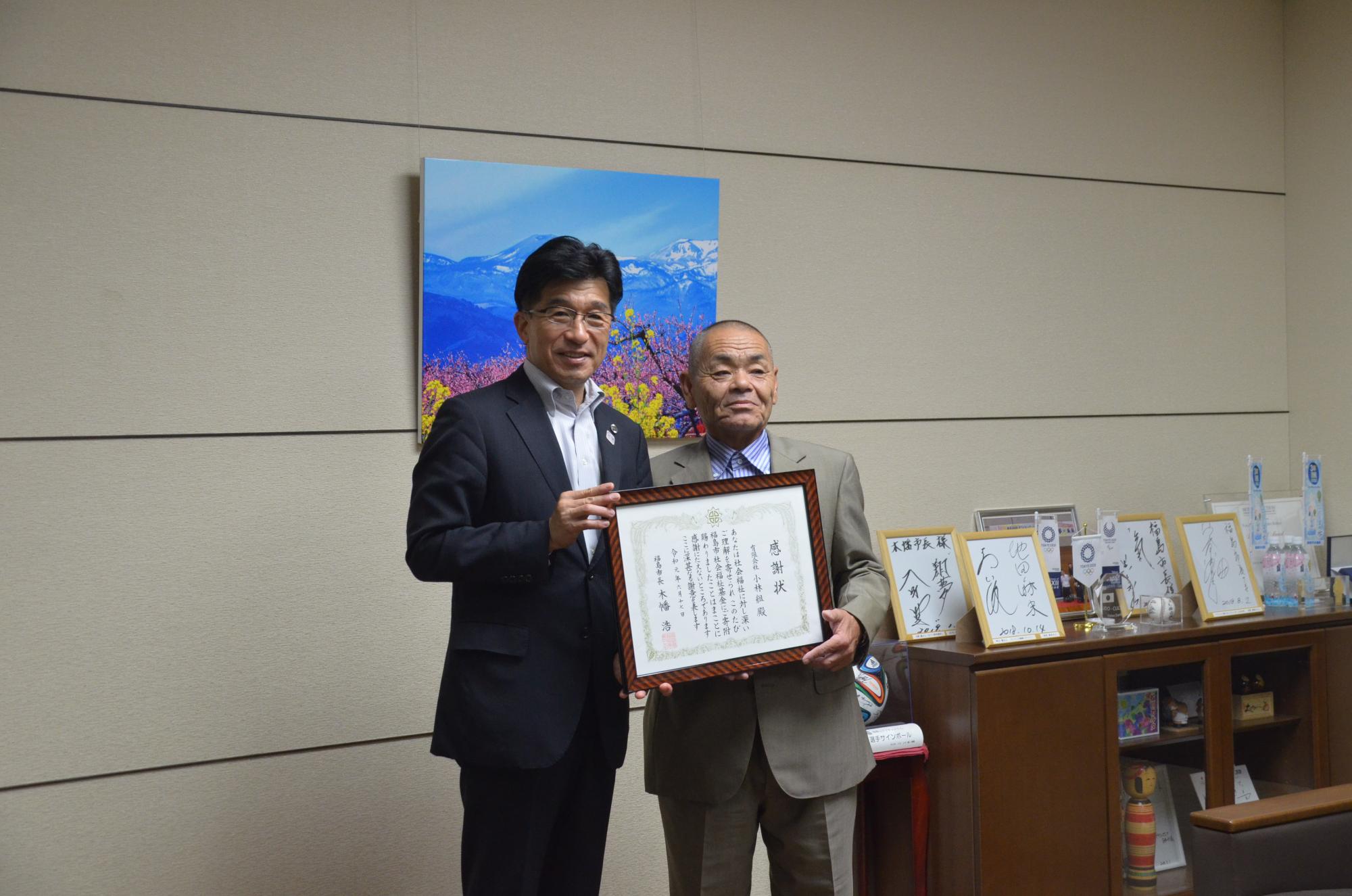 有限会社小林組代表取締役の小林様と市長が額縁に入った感謝状を一緒に持ち記念撮影している写真