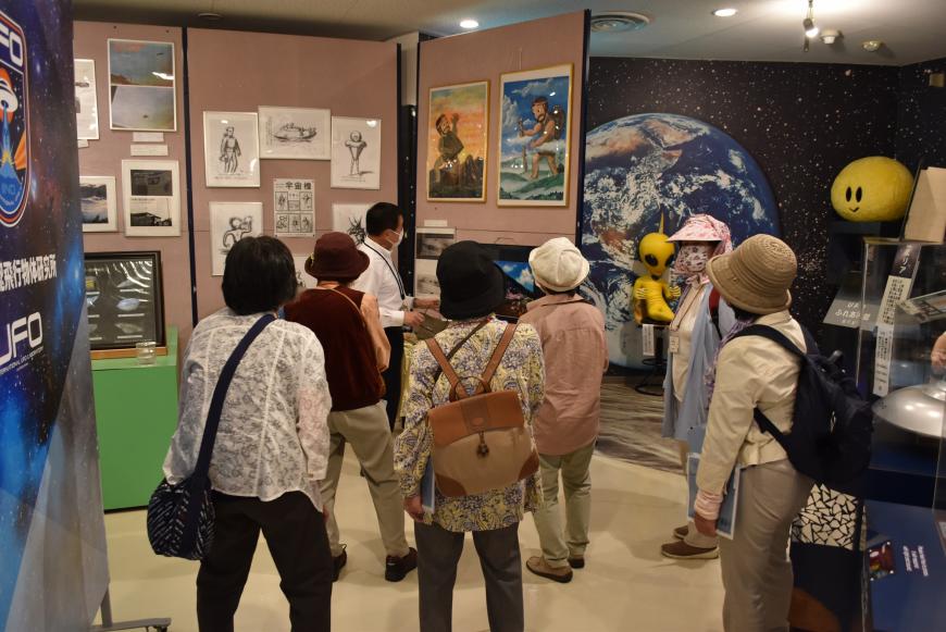 室内に展示された絵や資料の説明を係の方から受けている参加者の写真