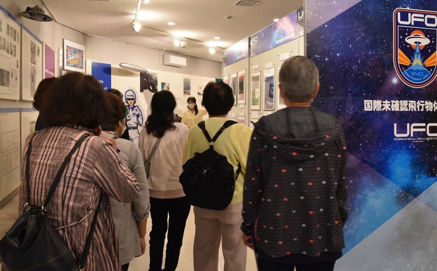 資料や写真が展示されたUFOふれあい館の中を見学している参加者の写真