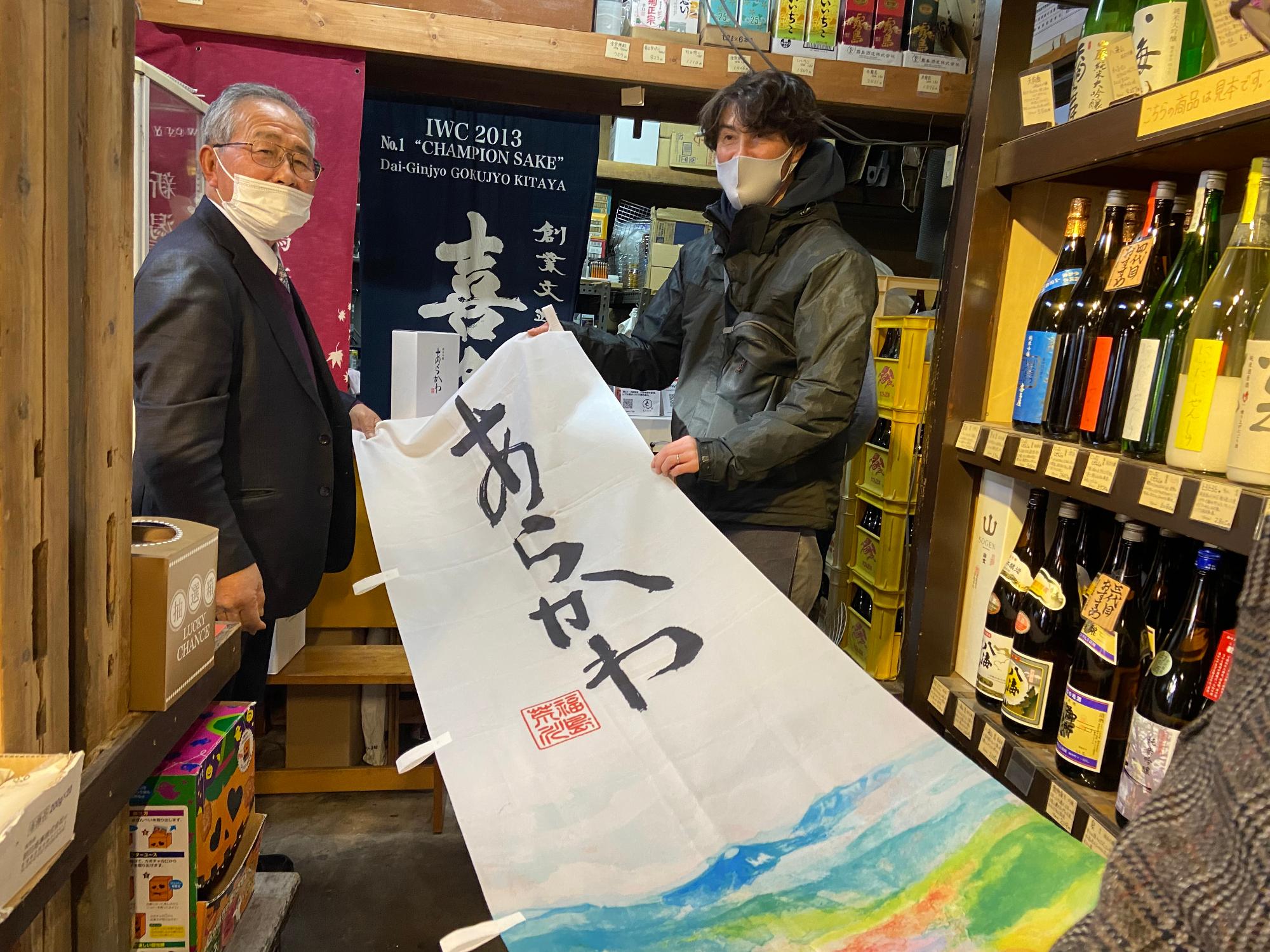 酒店内で「あらかわ」と書かれた旗を男性2人が持っている写真
