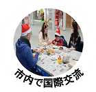 市内で国際交流(サンタ帽やトナカイの角のカチューシャをした人たちが交流をしている写真)
