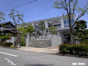 建物周辺に木が数本植えられた永井隆記念館を道路側から撮影した外観写真