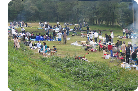 芝生の広がる広場で芋煮会を楽しむ沢山の参加者達の写真