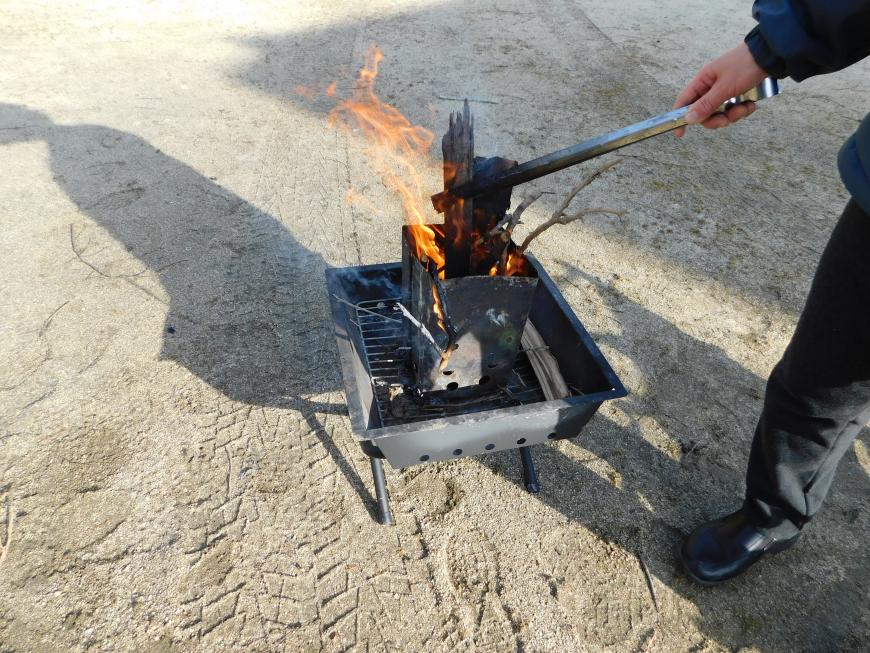 屋外で火おこしが行われキャンプの準備がされている様子の写真