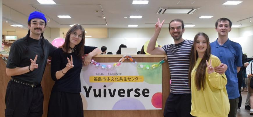 「福島市多文化共生センターYuiverse」と書かれた紙が貼られたパーテンションの両側に笑顔でピースサインをした5名の外国人の方が立っている写真