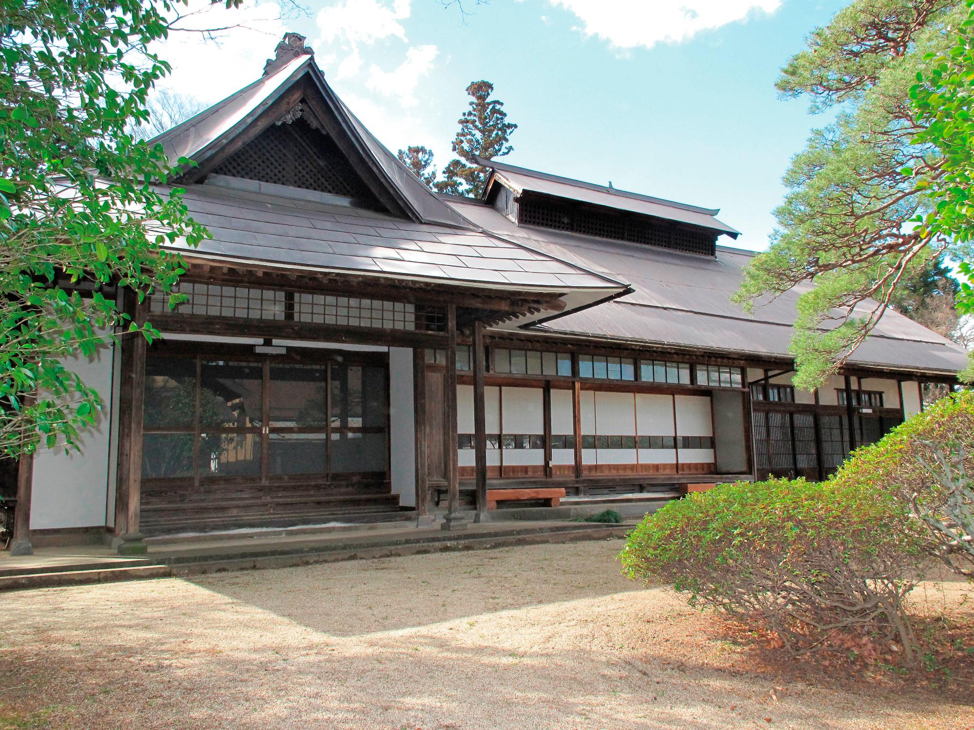 周囲に木が植えられ和風な旧佐久間邸を正面から撮影した外観写真