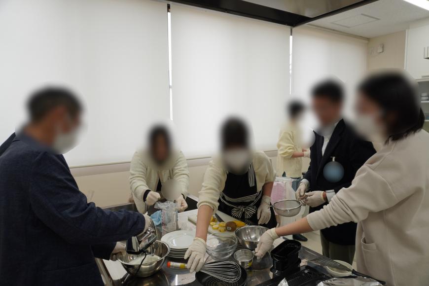 男性2名はスーツ姿で女性3名は腕をまくってパンケーキ作りを行っている様子の写真