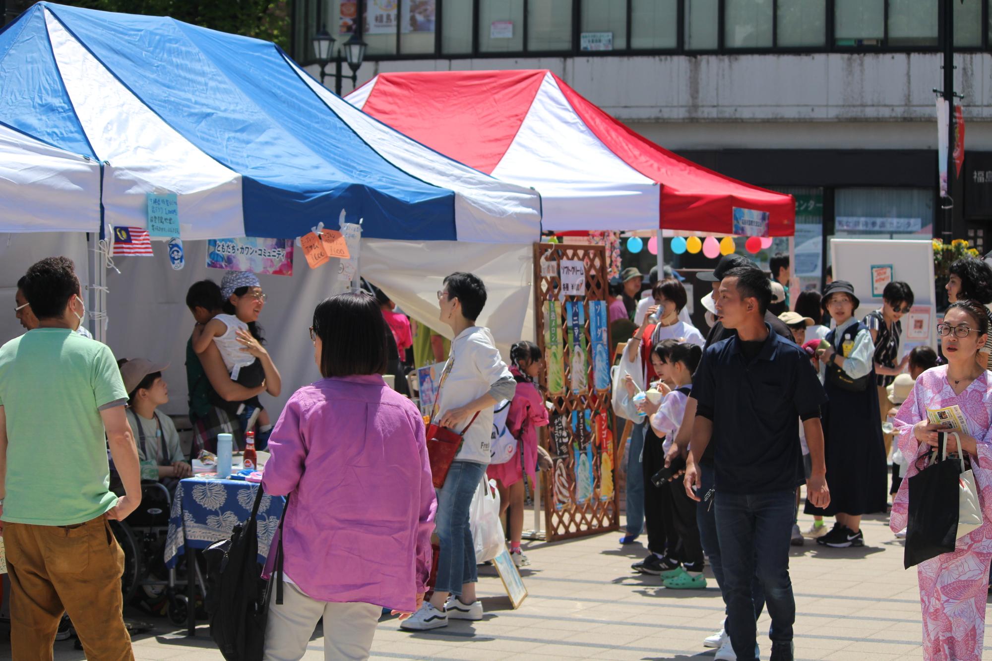赤や青のストライプのテントのイベントブースの写真