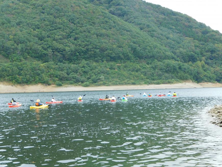 参加者達がカヤックに乗りダム湖内を散策する様子の写真
