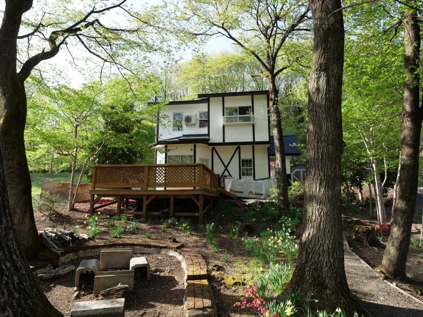緑に囲まれた山の中にある2階建てのログハウスの外観写真