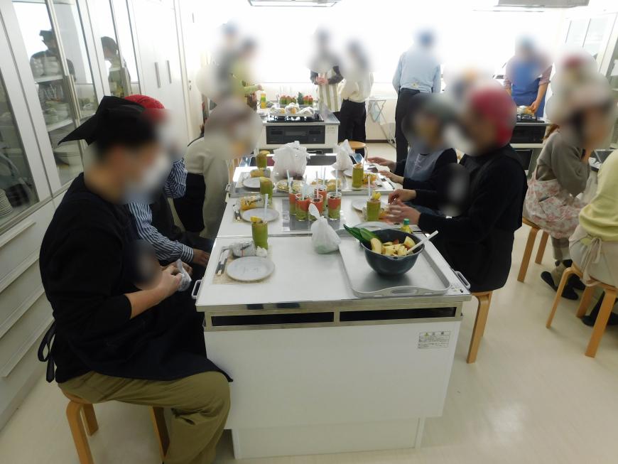 出来上がった料理が並べられ1グループが席に座っている写真