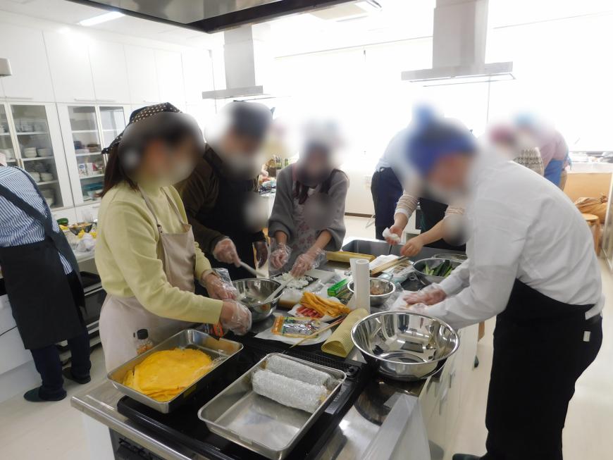 イベントに参加した男女が料理をする様子の写真