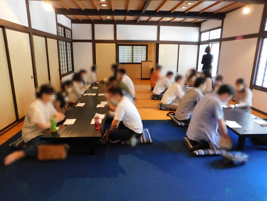 テーブルが2列に設置され食事が終わり参加者達が個別トークする様子の写真