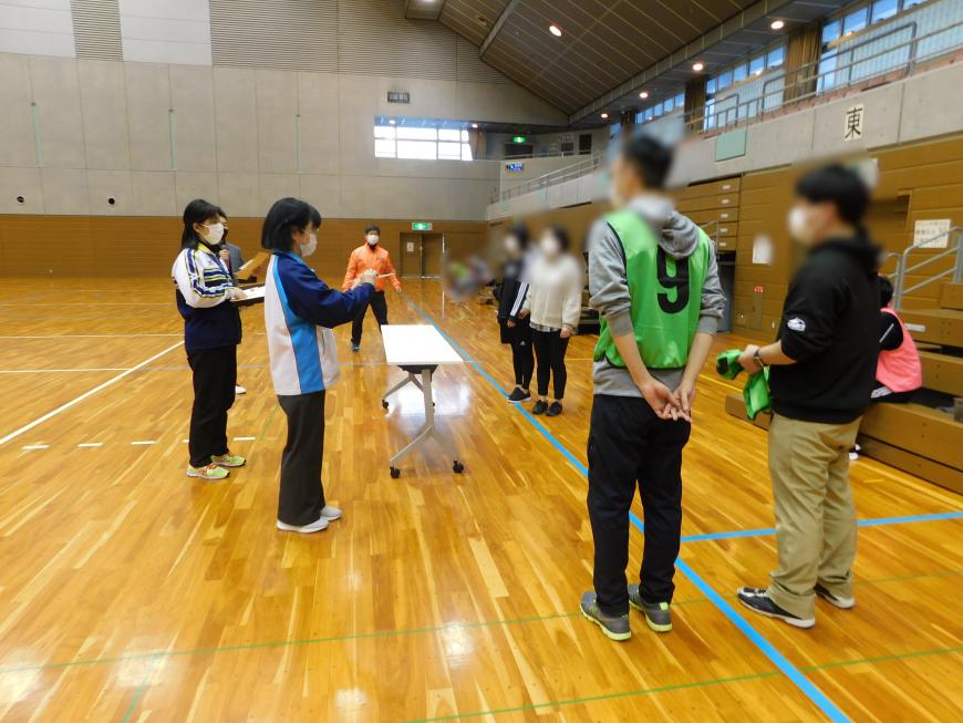 企画担当者が前に立って、勝ったチームにお食事券をプレゼントする様子の写真
