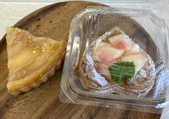 透明の容器に入った桃の果肉入りのパンとカットされたタルト生地のお菓子の写真