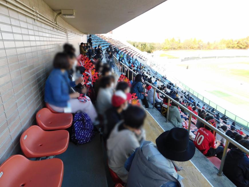 参加者達がスタンド席に座り試合観戦をする様子の写真
