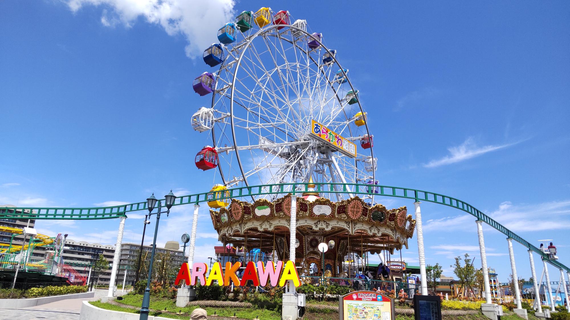 2人乗りのスカイサイクルが横ぎり、観覧車やメリーゴーランドなどの乗り物がある、あらかわ遊園の写真
