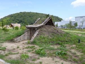 屋根が土屋で、屋根と地面がつながっている竪穴住居の写真