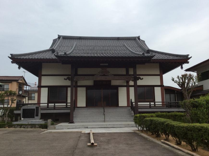 中央に手すりのついたコンクリートの階段の上に、白い壁で軒が広い屋根のある宝林寺が建っている写真
