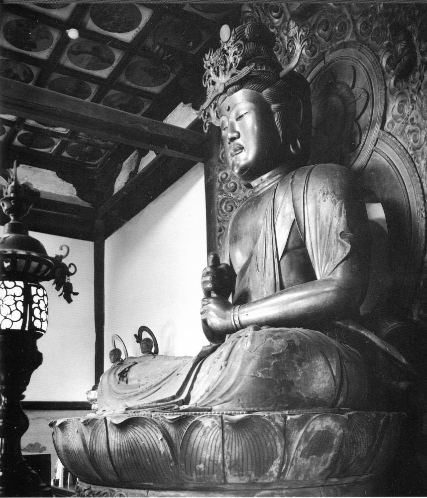 胸の前で左手の人差し指を立てて右手の拳で包み込むポーズで座禅をしている杉目大仏の坐像を横から写した白黒写真