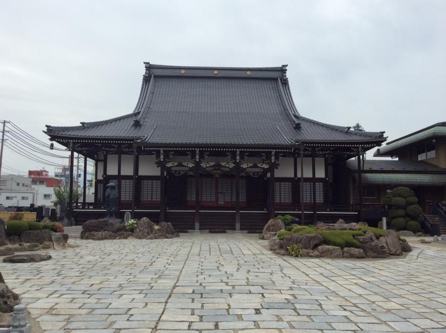 石畳が敷かれた敷地の中に建っている大きな屋根をした康善寺の写真