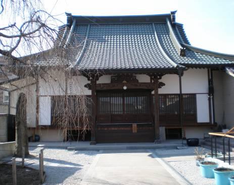 歩道の両脇に玉砂利が敷かれ、奥に白い壁と反った瓦屋根の誓願寺の建物がある写真