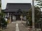 砂利の道の中央に四角い石が敷かれ、その奥に白い壁と濃いグレーの屋根の東安寺がある写真