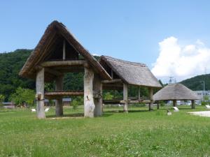 手前に2階建ての掘立柱建物が2棟、その奥に平屋建ての掘立柱建物が建っている写真
