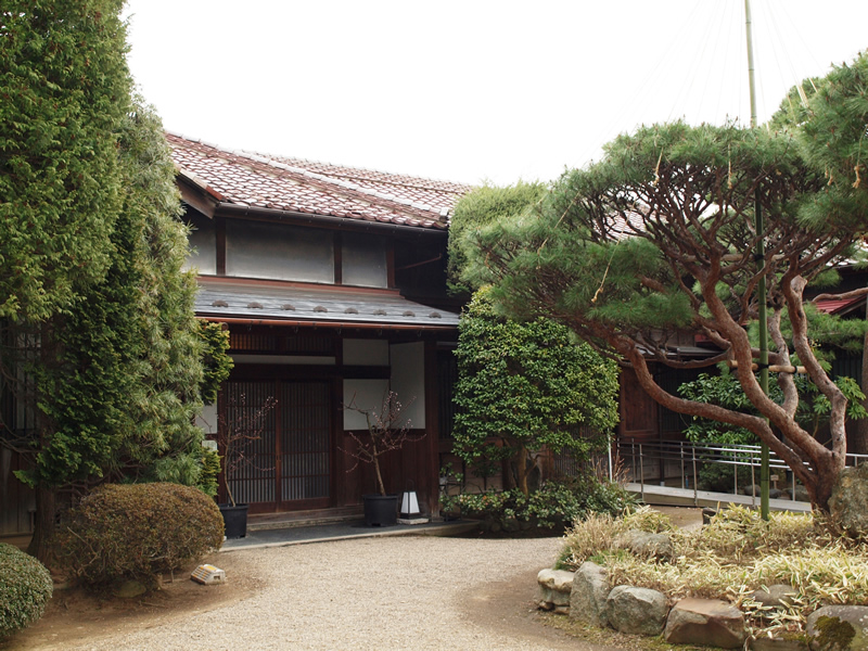 整備された植栽の奥に建っている御倉邸の写真