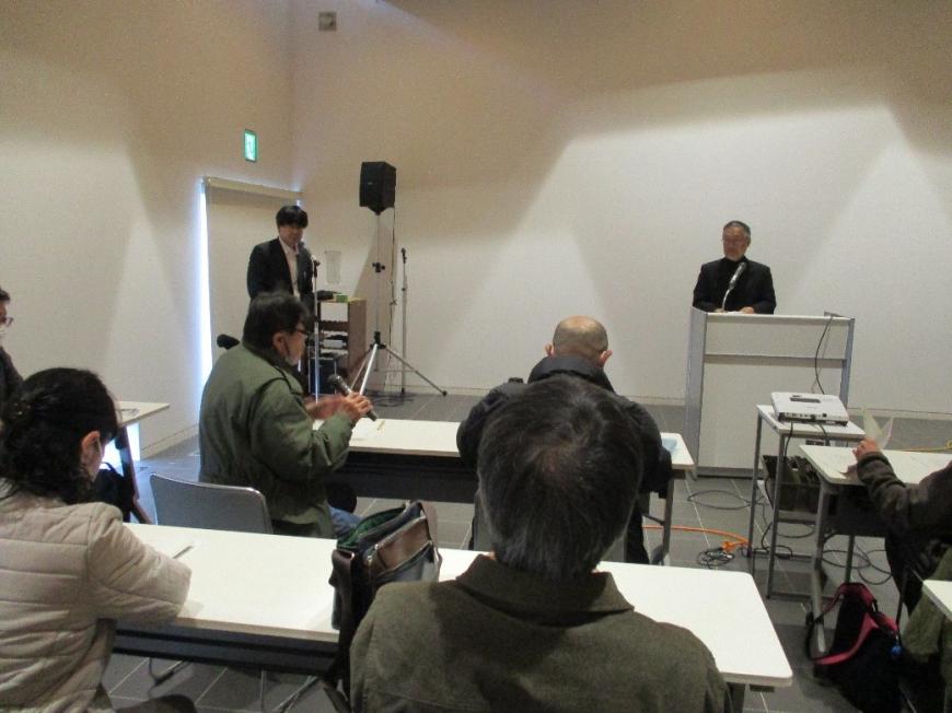 参加者の男性が講師にマイクを使い質問をしている様子を撮影した写真