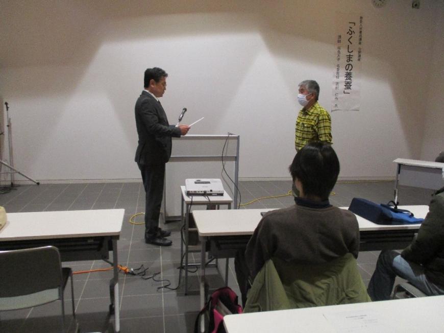 受講者の男性が修了証を受け取るため背筋を伸ばし講師の話を聞いている写真