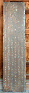 縦長の板に文字が6行ほど刻まれている石母田供養石塔模刻(木製)の写真